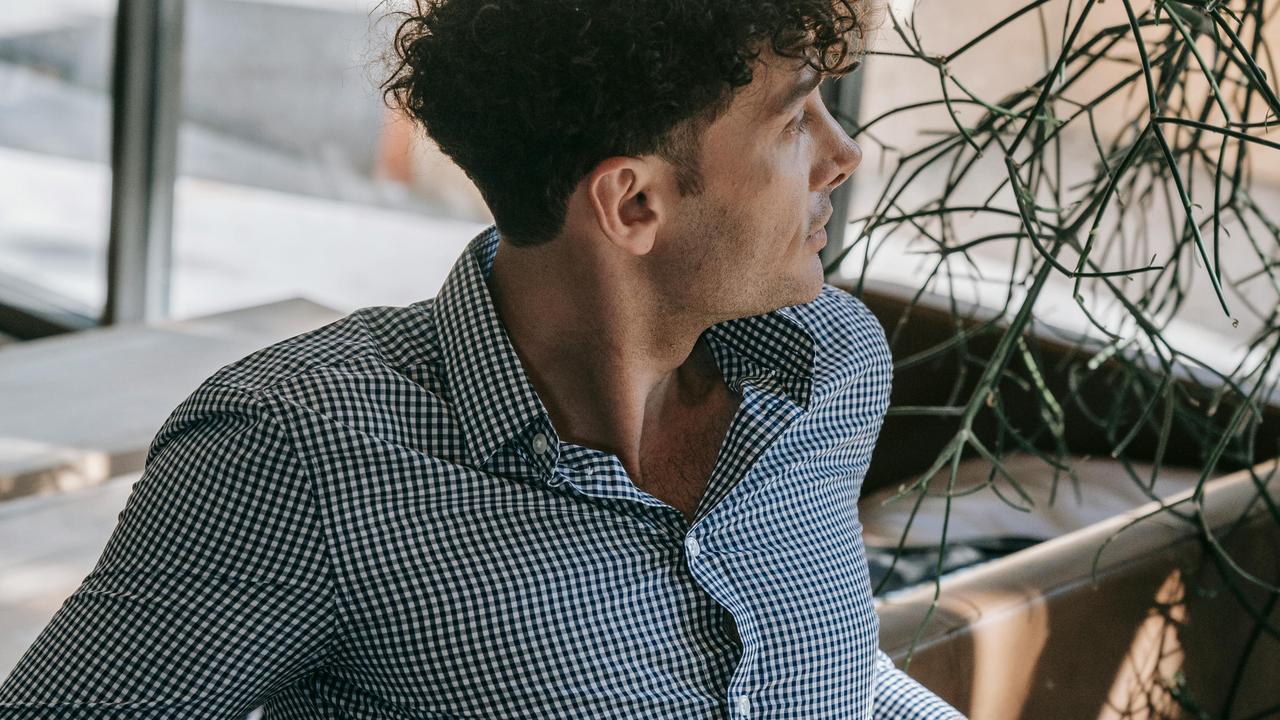 A man looks at a distance while sitting on a couch.