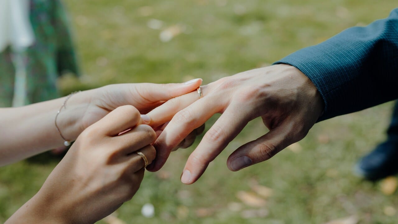 A woman putting on a wedding ring on a man