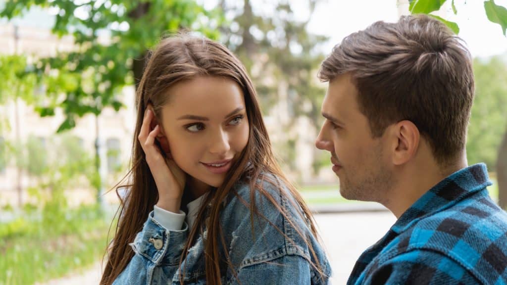 Young couple looking at each other outdoors, the woman in a denim jacket.
