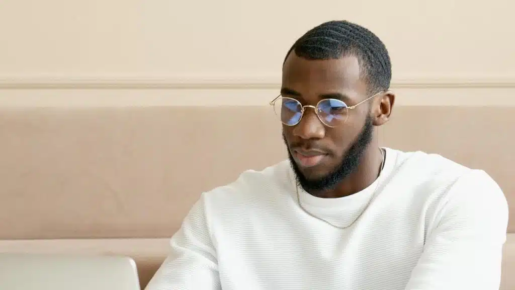 A man in glasses and a white shirt working on a laptop.