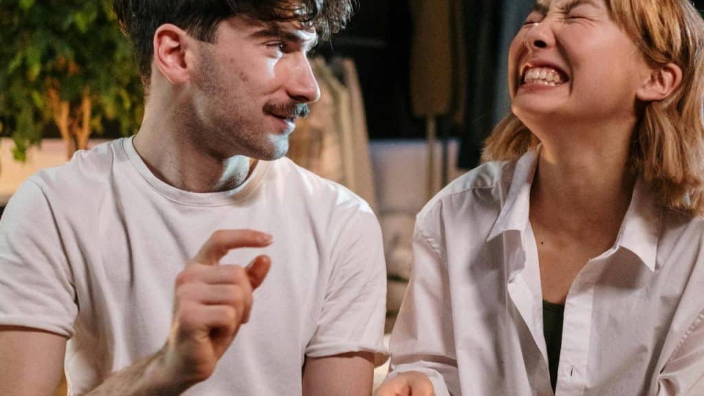 A man and woman laughing together while sitting close indoors.