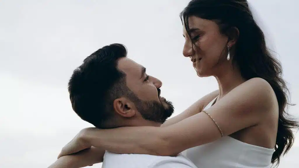 A couple lovingly embracing and gazing into each other’s eyes outdoors.