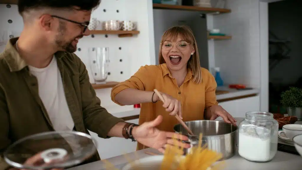 A couple laughing together in the kitchen