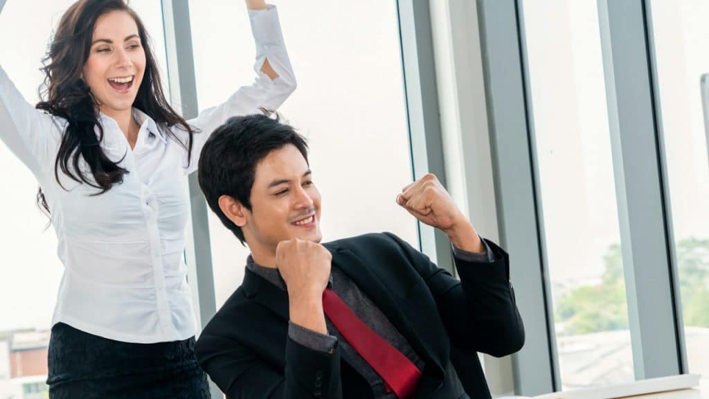 A man and woman business people celebrating their success in an office.