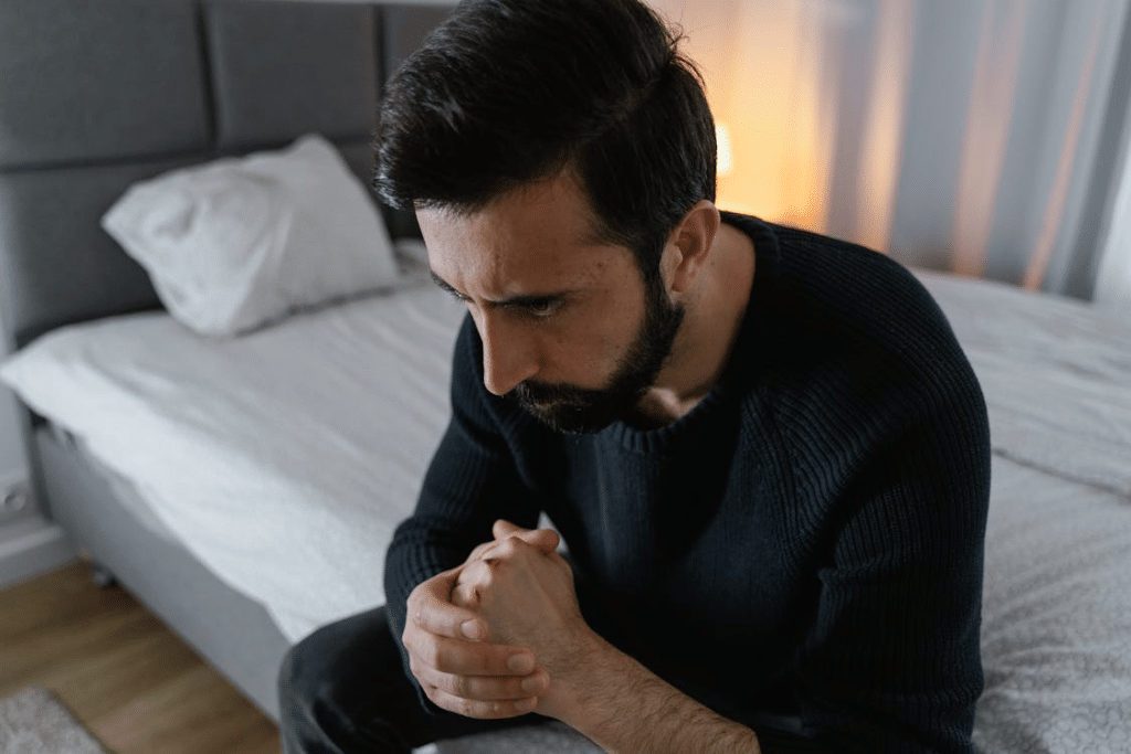 A Bearded Man in Black Sweater Sitting on the Bed