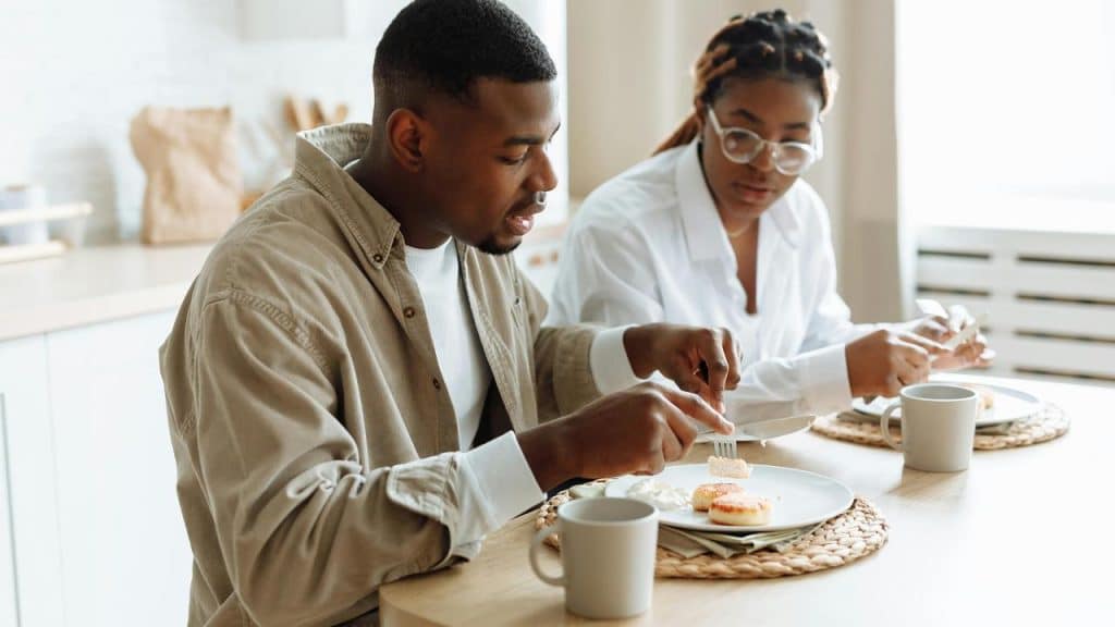 A man and woman sitting at a table eating breakfast together.