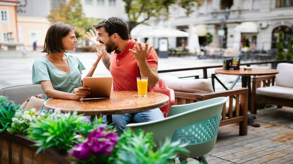 A couple fighting at an outdoor cafe