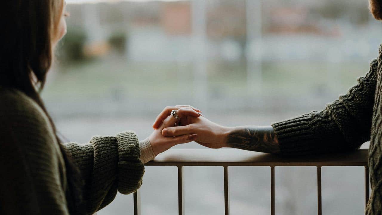 A couple holding hands while standing by a railing.