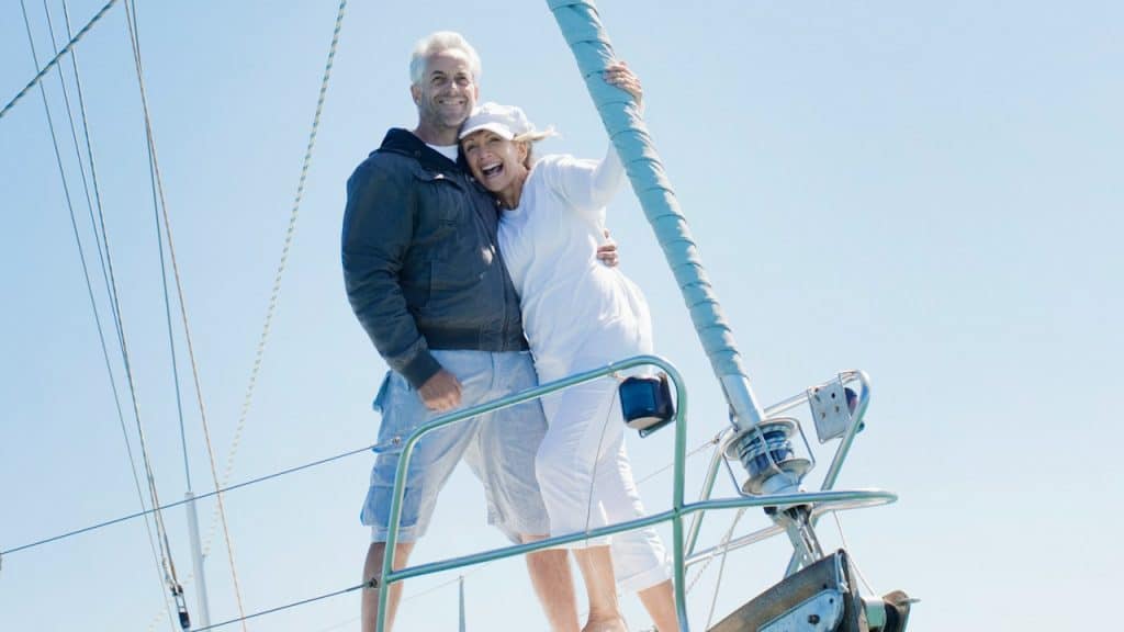 A couple standing close together on the bow of a ship.