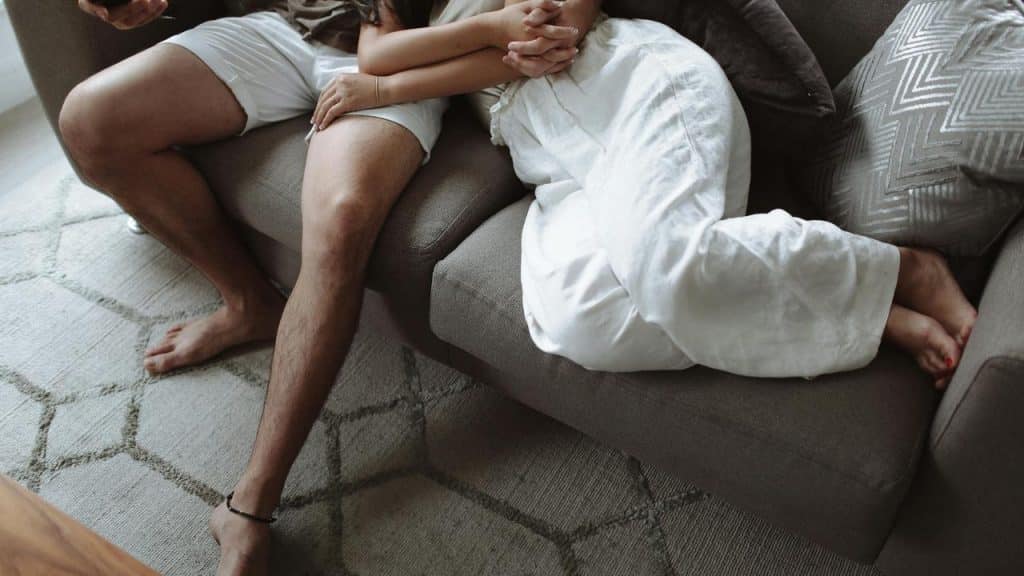 A couple relaxing on a couch with their legs intertwined.