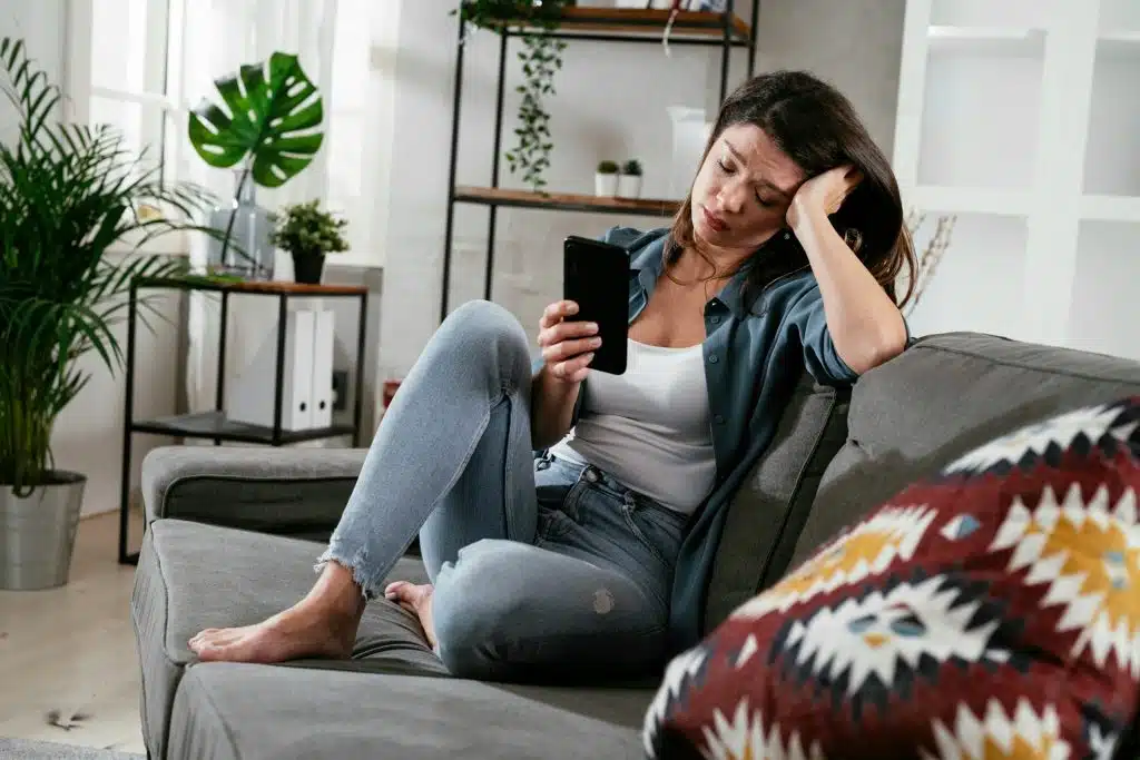 An upset woman looking at her smartphone.