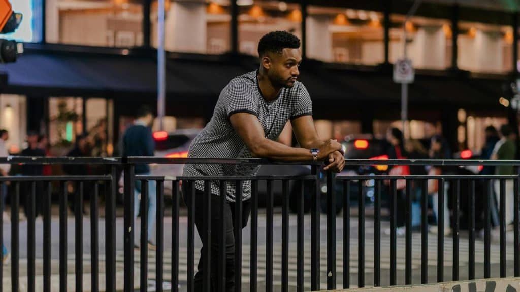 A man leaning on a railing in a city at night.