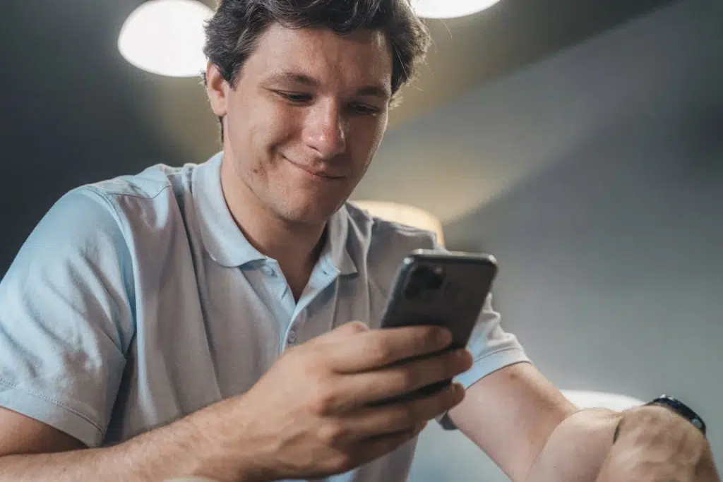 Man in blue polo shirt holding a smartphone