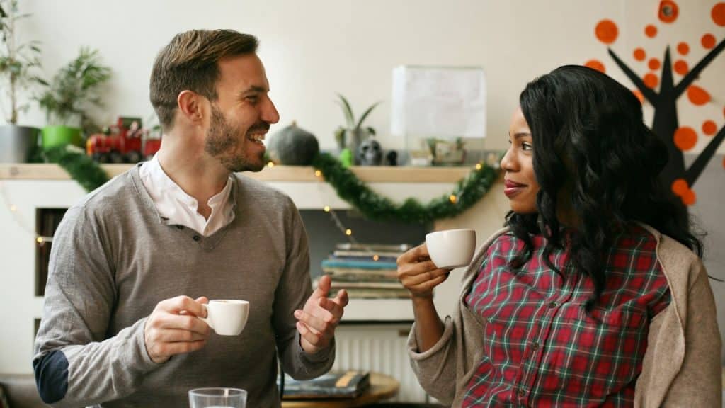 A couple talking and smiling while sitting in a cafe.