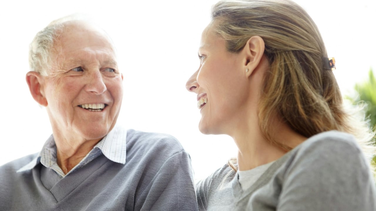 An older man smiling at a younger woman.