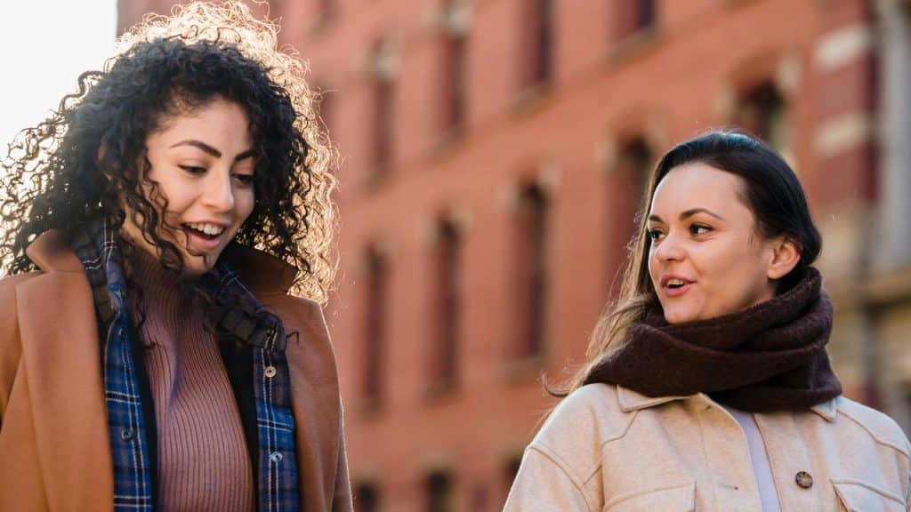 A pair of women walking outdoors and talking cheerfull