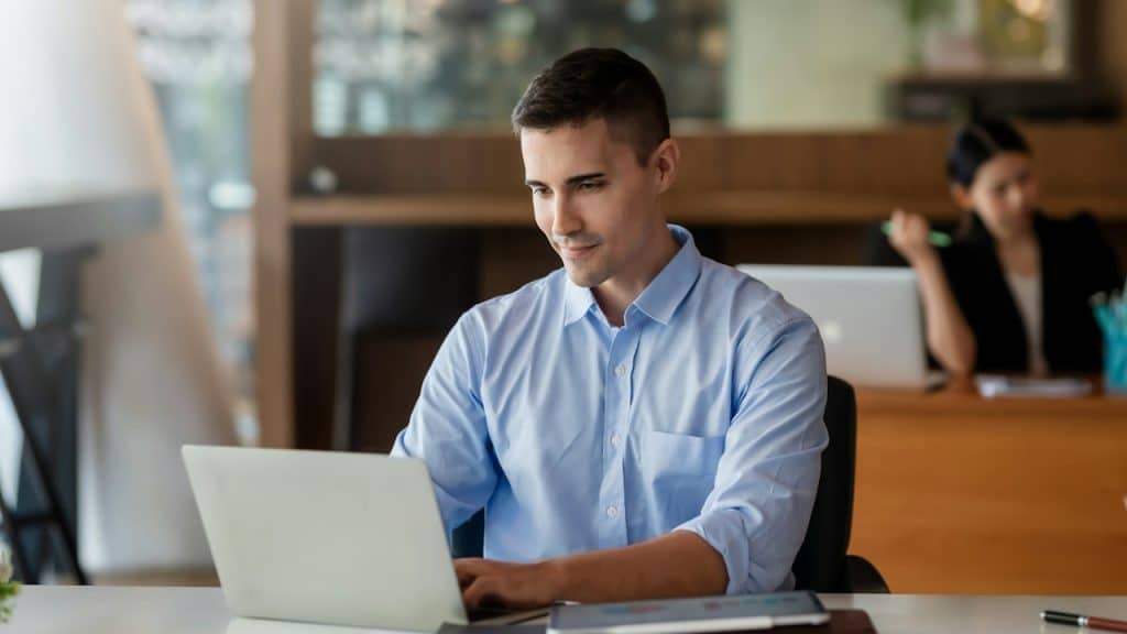 A man working on a laptop in his office.