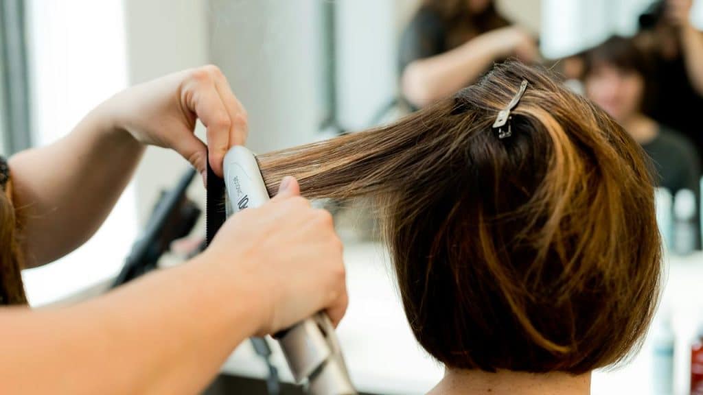 A person having their hair straightened at a salon.
