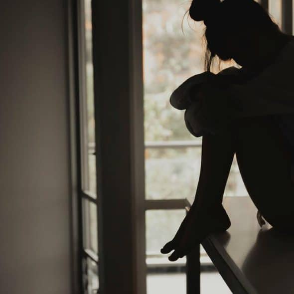 A silhouette of a woman sitting on a countertop.