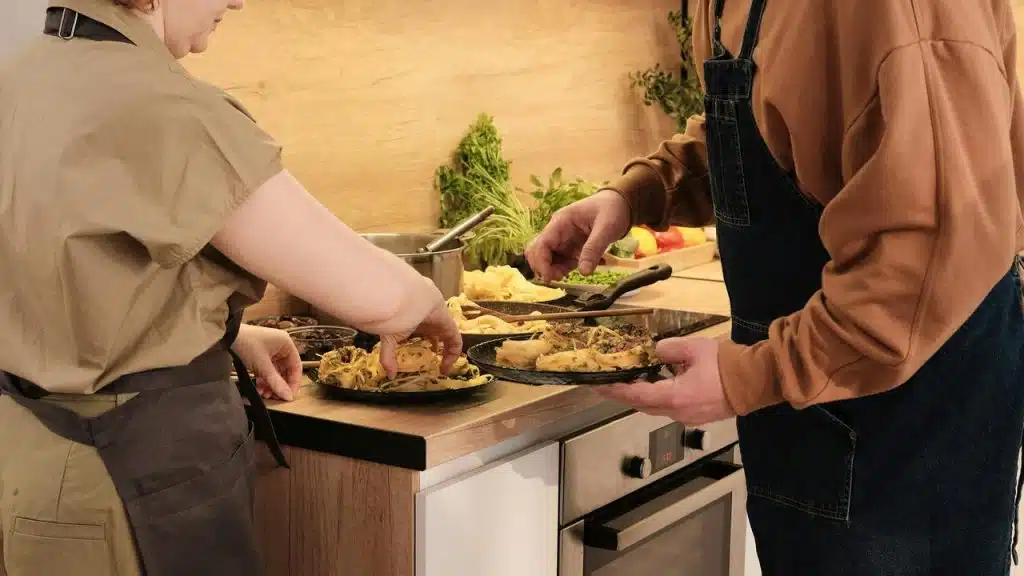 A couple cooking tortillas together in a kitchen.