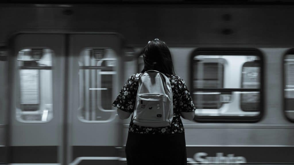 A woman standing i front of a subway train.
