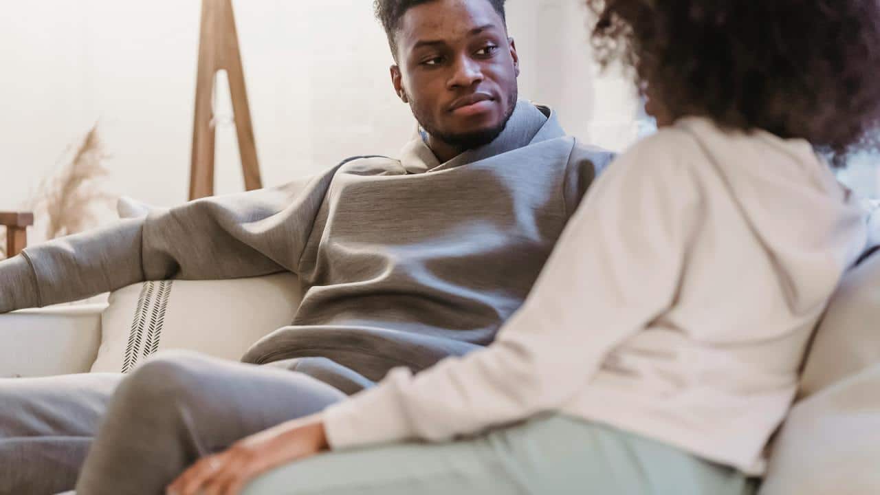 A man staring intently at a woman as they sit on a couch.