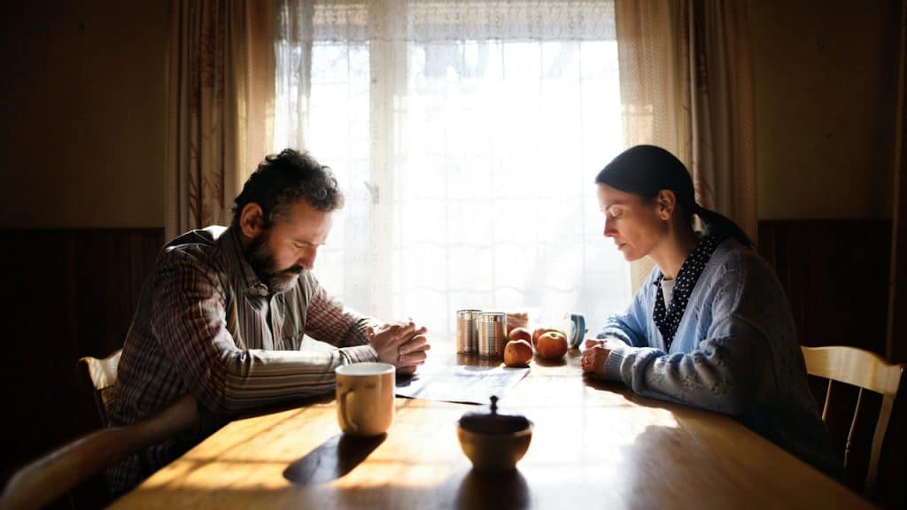 A man and a woman sitting silently at a dinner table