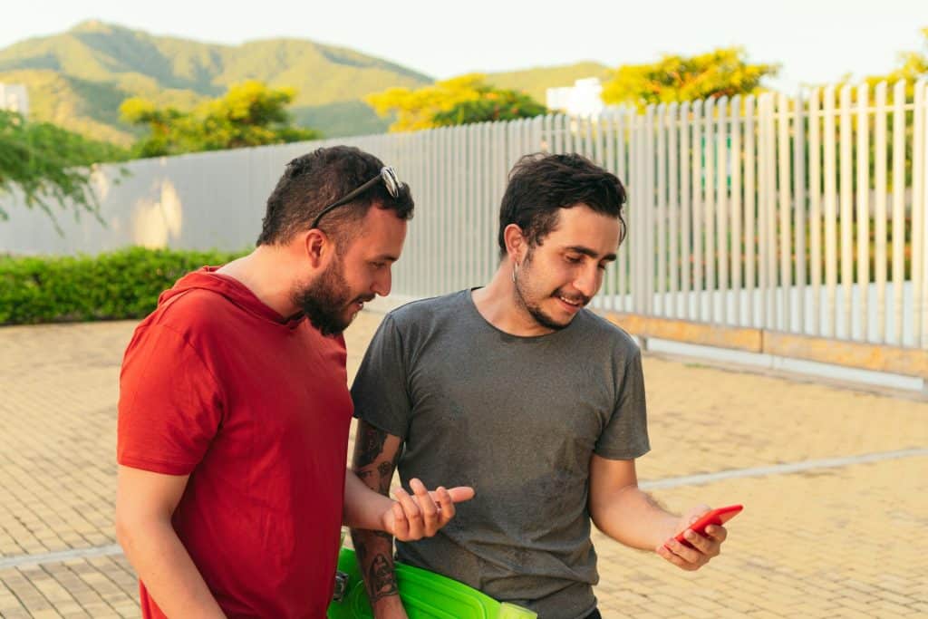 Friends looking at the phone while in a park.