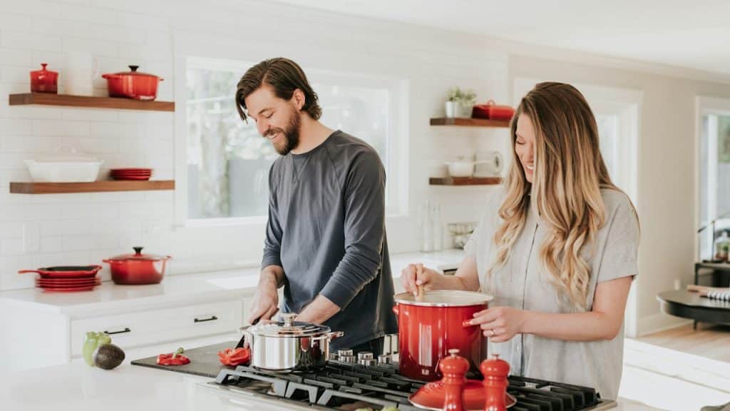 A man and a woman cooking meals together in a kitchen.