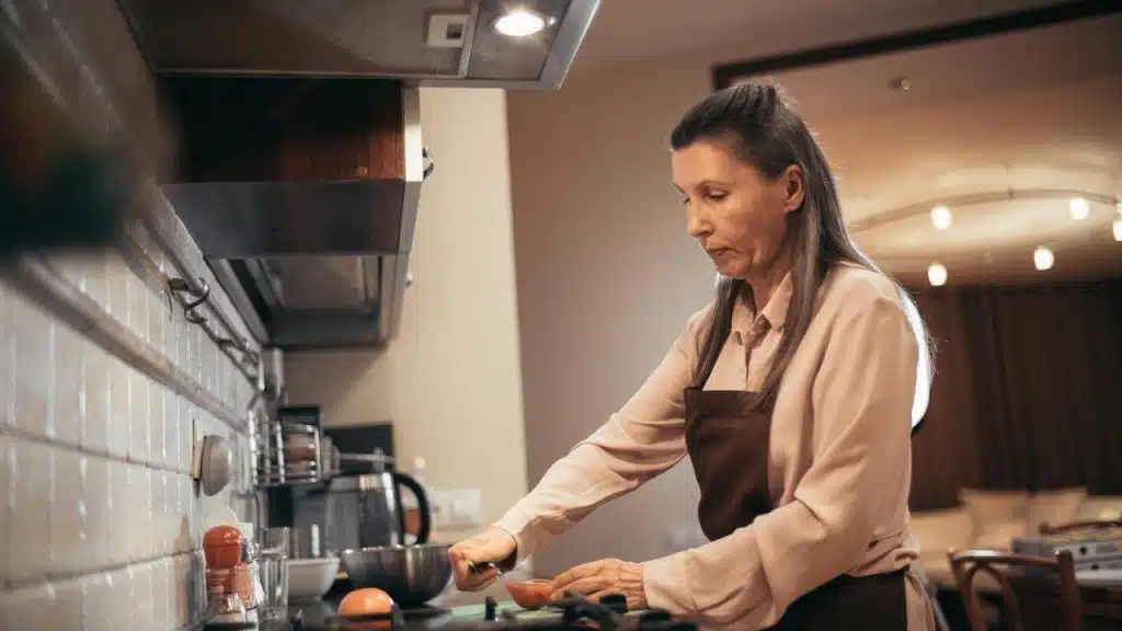 A woman cooking in a kitchen while wearing an apron.