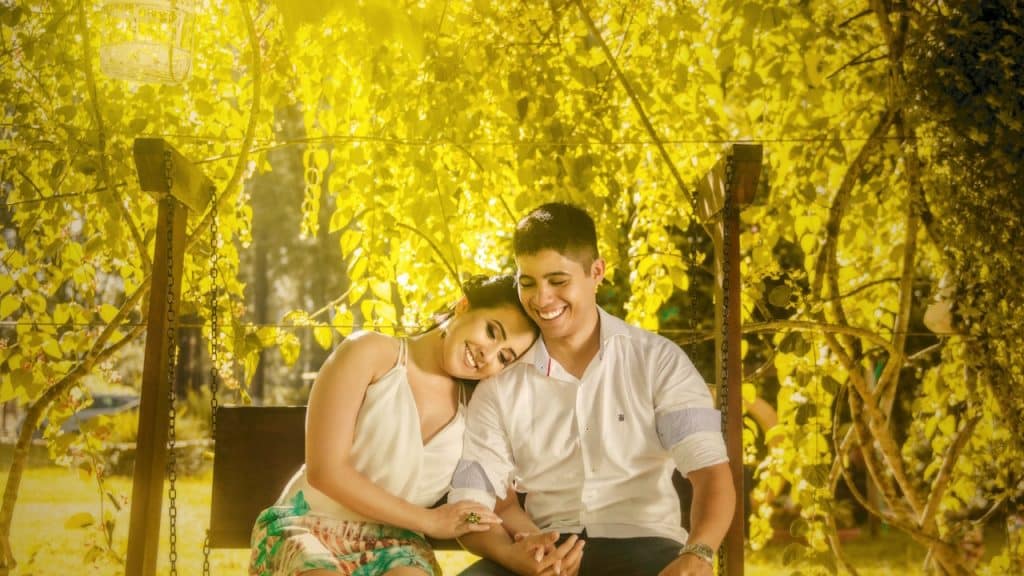 A man and woman sitting on a bench in a park.