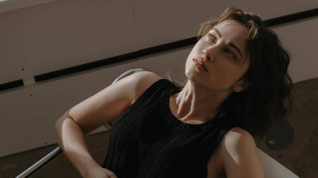 A woman reclining in a chair while looking upward with a thoughtful expression.