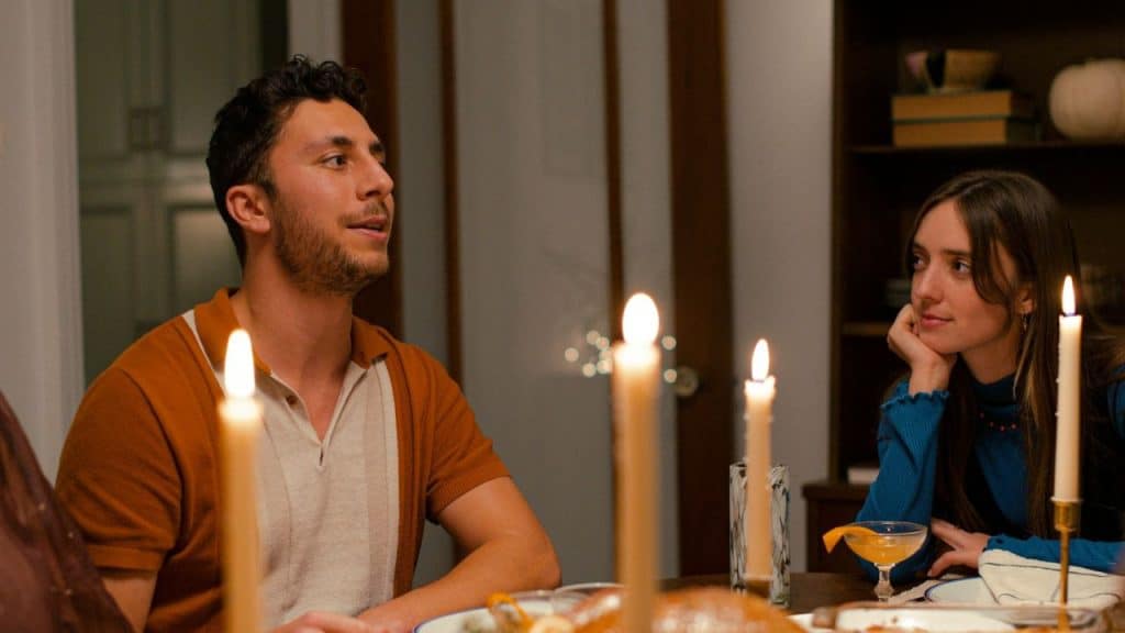 Two people seated at a dinner table lit by several tall candles.