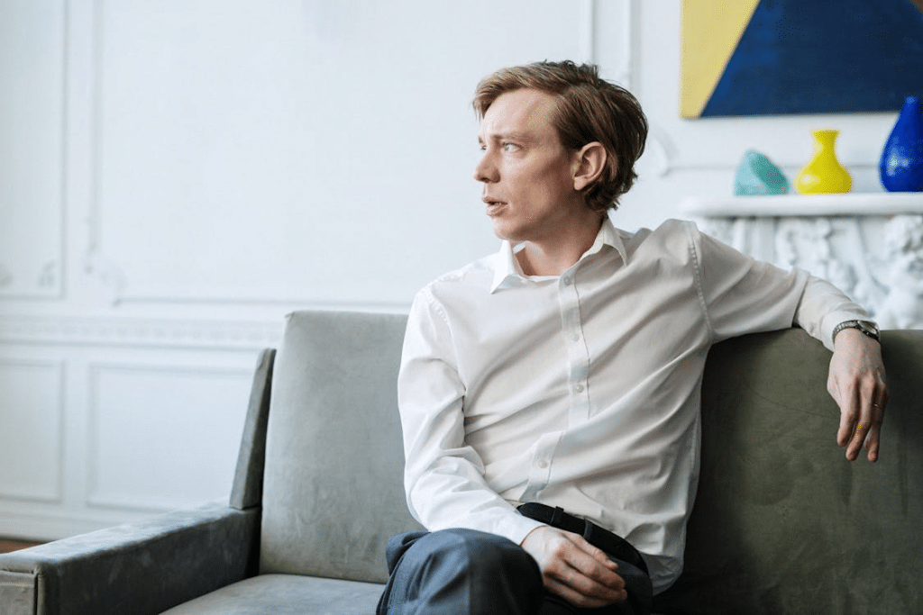 Woman in White Dress Shirt Sitting on Gray Couch