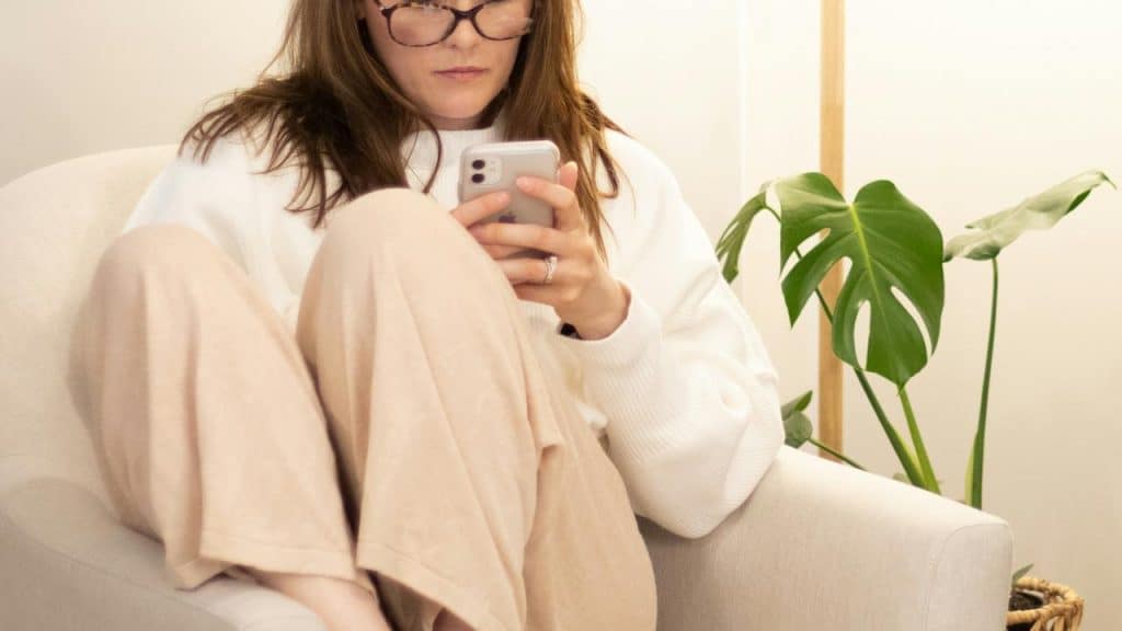 A woman sitting in a chair looking at her smartphone.