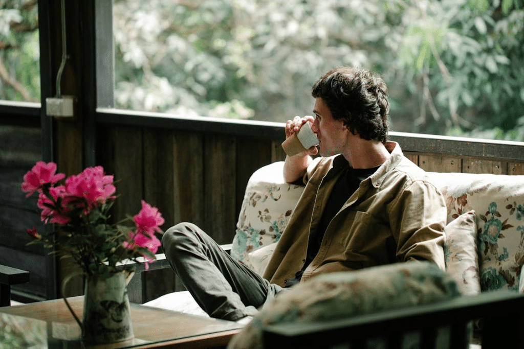 Man enjoying coffee on sofa on house terrace in countryside