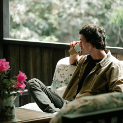 Man enjoying coffee on sofa on house terrace in countryside