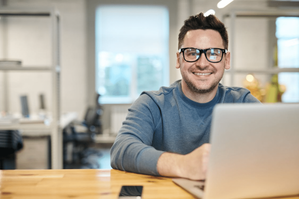 A man smiling while using a laptop