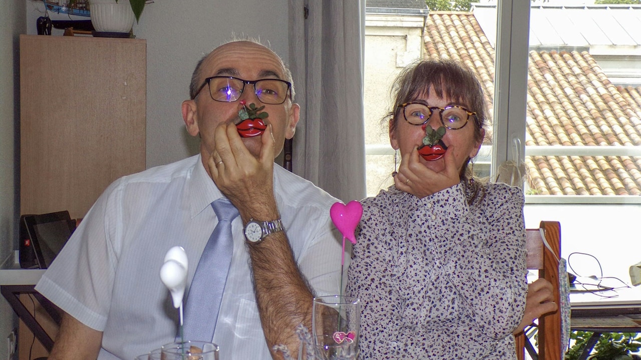 An old man and a woman sitting at a table posing for a picture.