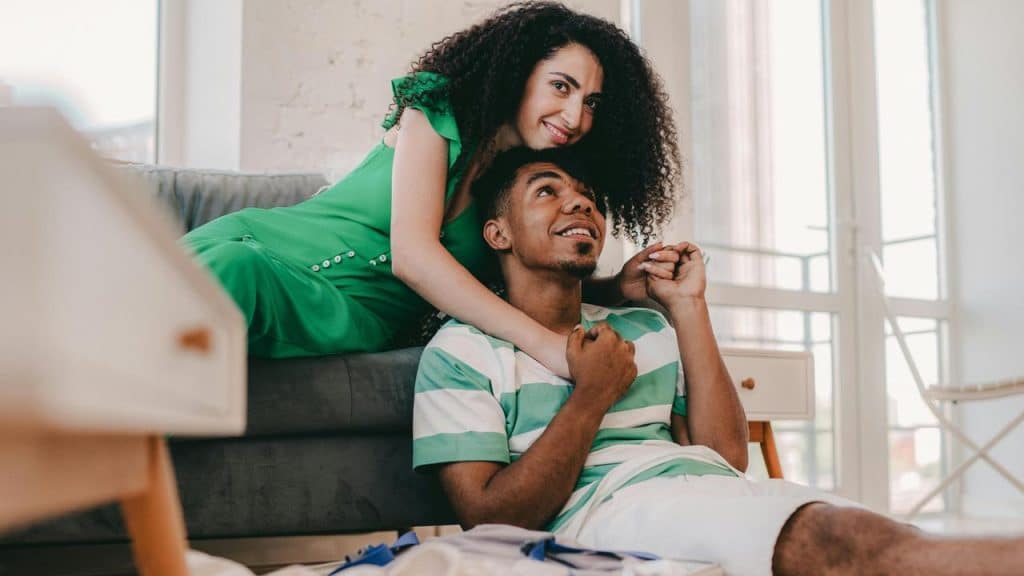 A couple smiling affectionately while sitting together in a bright living room.