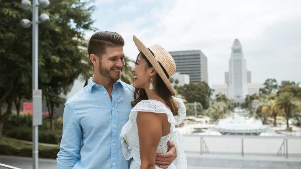 A couple hugging and smiling in an outdoor city setting.