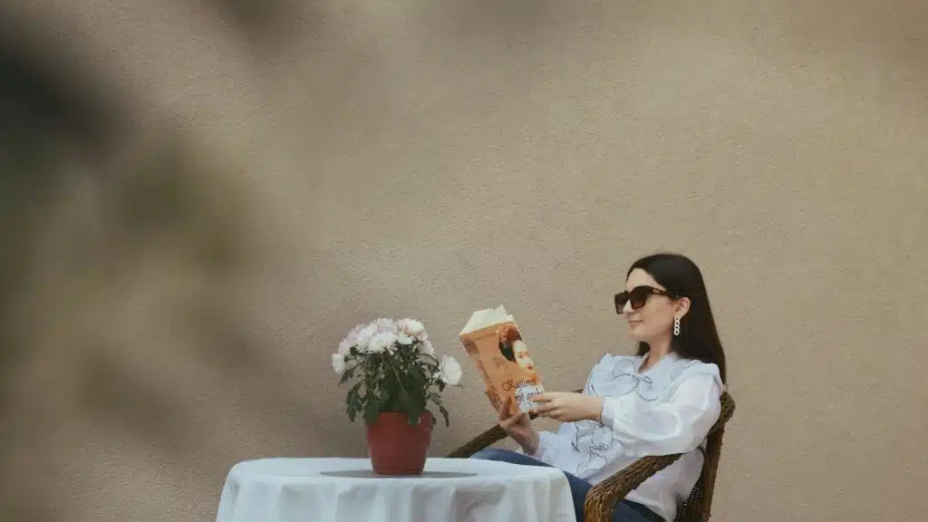 A woman sitting at a table, reading a book.