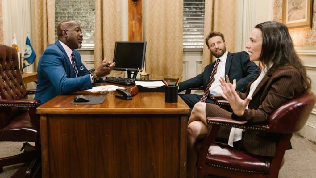 Three businesspeople in a formal office setting having an animated conversation.