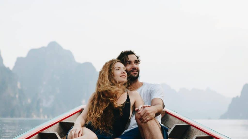 A couple sitting on a boat enjoying the mountain view.