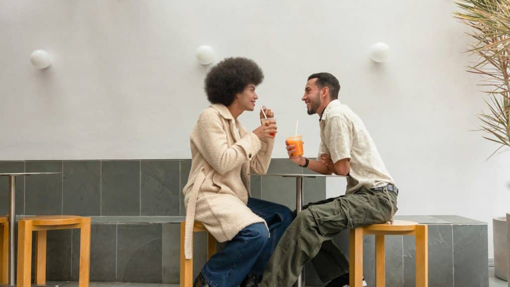 A couple sitting at a table and smiling at each other while having drinks.