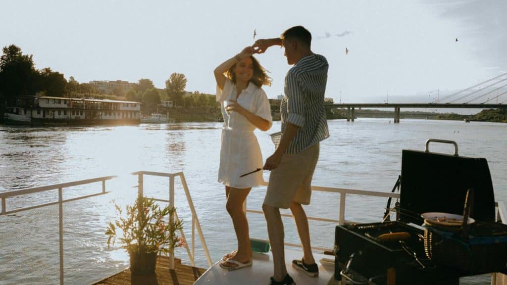 A couple dancing together on a boat deck at sunset.