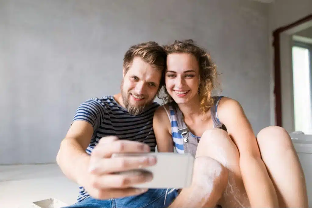 A man and woman taking a picture to post online