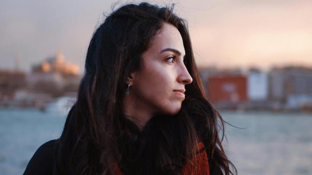 A woman looking to the side near a waterfront.