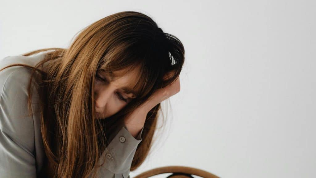 A woman resting her head on her hand with a tired, downcast expression.