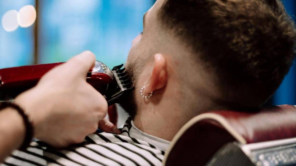 A person getting their beard trimmed with electric clippers.